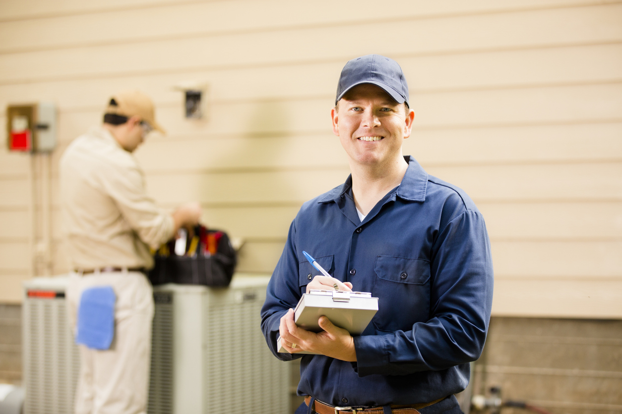 HVAC technician performing maintenance on air conditioning unit